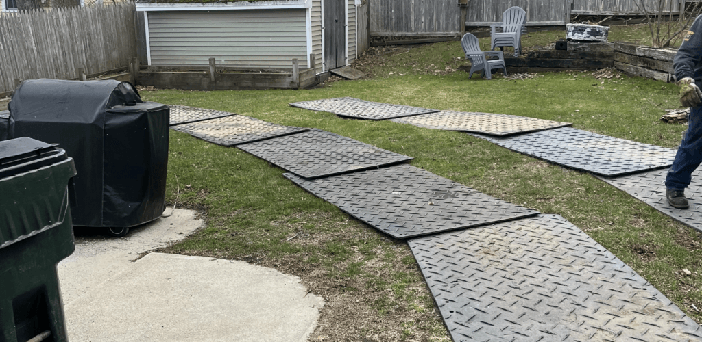Ground protection mats laid across a lawn to protect the turf from equipment during a tree removal