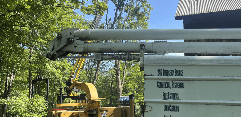 PV Tree Service crane truck with its boom extended beside a barn in Franklin County, Massachusetts
