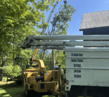 PV Tree Service crane truck with its boom extended beside a barn in Franklin County, Massachusetts